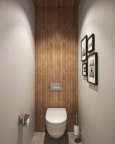 a white toilet sitting in a bathroom next to a wooden paneled wall with pictures on it