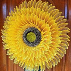 a large yellow sunflower is hanging on the front door