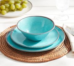 a table set with plates and bowls on top of each other, next to green grapes