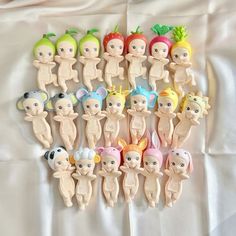 there are many small plastic dolls on the bed together, one is wearing a headband