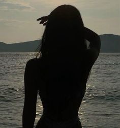 a woman standing in the water with her back to the camera