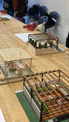 people standing around a table with model houses on it and plants in the middle one