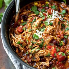 a large pot filled with chicken, black beans and veggie chili soup on top of a wooden table