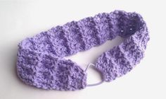 a purple crocheted headband on a white surface