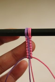 a hand holding a black crochet hook with pink and purple thread