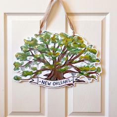 a door hanger with a tree painted on it and the words new orleans written in white