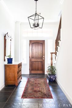 an entryway with a rug on the floor and a light fixture hanging from the ceiling