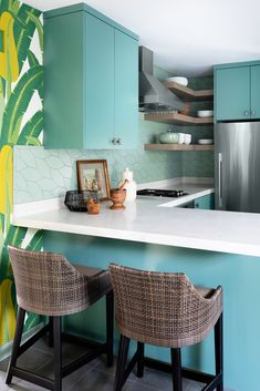 two wicker chairs sit at the counter in front of a blue painted kitchen island