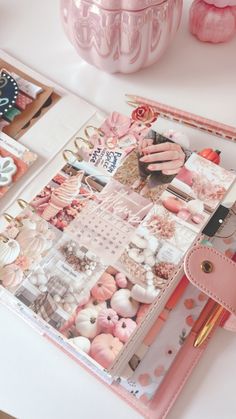 an open planner book sitting on top of a table next to pink decorations and other items