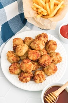 some fried food on a white plate next to ketchup and french fries with dipping sauce