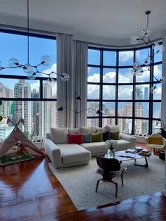 a living room filled with furniture and large windows overlooking the cityscape in the distance