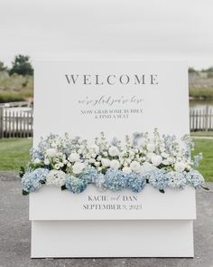 a welcome sign with blue and white flowers