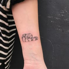 a small elephant tattoo on the left inner arm, with two smaller elephants behind it