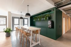 an office with tables, chairs and plants on the wall