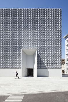 a man is walking in front of a white building with an open door that looks like he's coming out of it