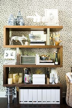 a shelf filled with lots of books on top of a hard wood floor next to a wall