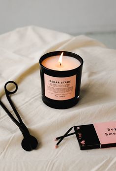 a candle and some scissors on a white sheet with a pink tag next to it