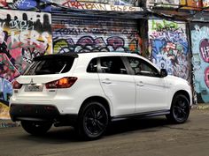 a white car parked in front of a graffiti covered wall