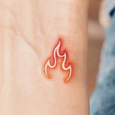 a small tattoo on the wrist of a woman's left arm with a red flame