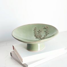 a green bowl sitting on top of two books