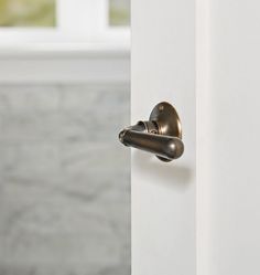 an open door with a handle on it in front of a marble wall and window