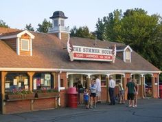 a group of people standing in front of a building with a sign that says the summer house