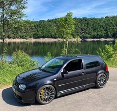 a black car parked in front of a lake