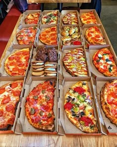 many different types of pizzas in boxes on a table