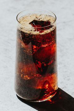 a close up of a drink in a glass on a table with a shadow from the floor