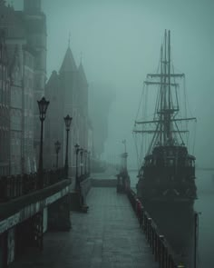 a boat is docked in the water near some buildings on a foggy day,