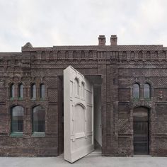 an open door is in the middle of a brick building with arched windows on both sides