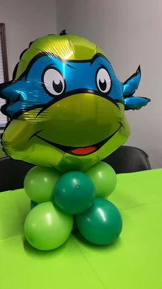 an inflatable turtle balloon sitting on top of a table next to green balloons