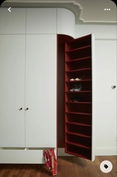 an open closet with shoes in it on the floor next to a white wall and wooden floors