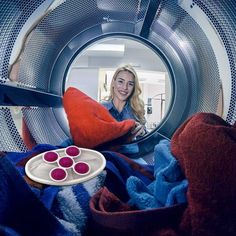 a woman sitting in front of a dryer holding a plate with fruit on it