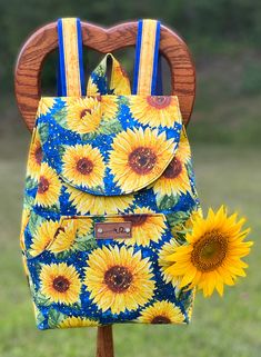 a blue and yellow bag with sunflowers on it sitting in front of a wooden chair