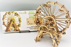 a wooden model of a ferris wheel next to an instruction book on how to build it