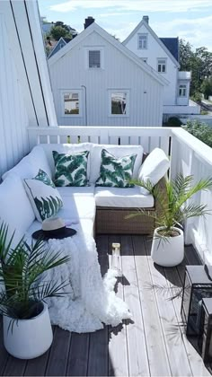 a white couch sitting on top of a wooden floor next to potted planters