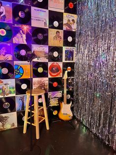 a room filled with lots of records and a guitar on top of a stand next to a curtain