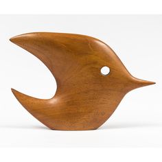 a wooden bird sculpture sitting on top of a white surface with holes in the side