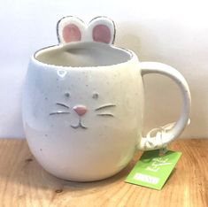 a ceramic mug with a cat's face painted on the side and ears sticking out