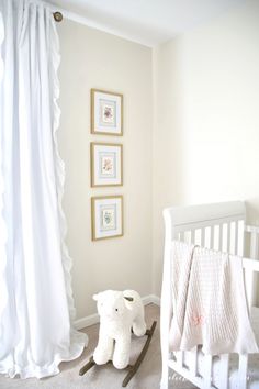 a baby's room with a white crib and pictures on the wall