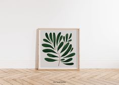 a green leaf print on a white wall above a wooden floor in an empty room