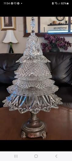 a glass christmas tree sitting on top of a wooden table