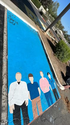 a mural painted on the side of a building with people standing around and looking at it