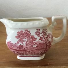 a red and white vase sitting on top of a wooden table