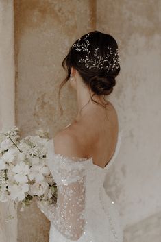 a woman in a wedding dress holding a bouquet of flowers and wearing a tiara