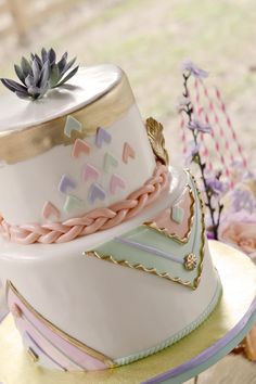 a three tiered cake is decorated with pastel colors and gold trimmings