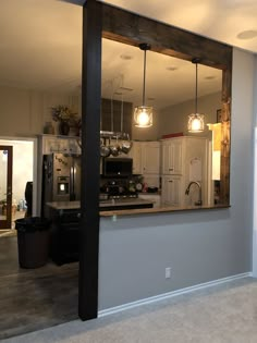 an empty kitchen and living room are reflected in the mirror on the wall above the sink