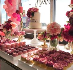 a table topped with lots of cupcakes and cakes next to a tall window