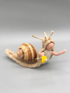 a needled toy snail with a yellow flower in its mouth on a gray background